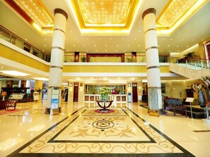 A spacious lobby with a central reception desk, multiple floors, and a decorative floor pattern. - Chengyang Detai Hotel (Qingdao)