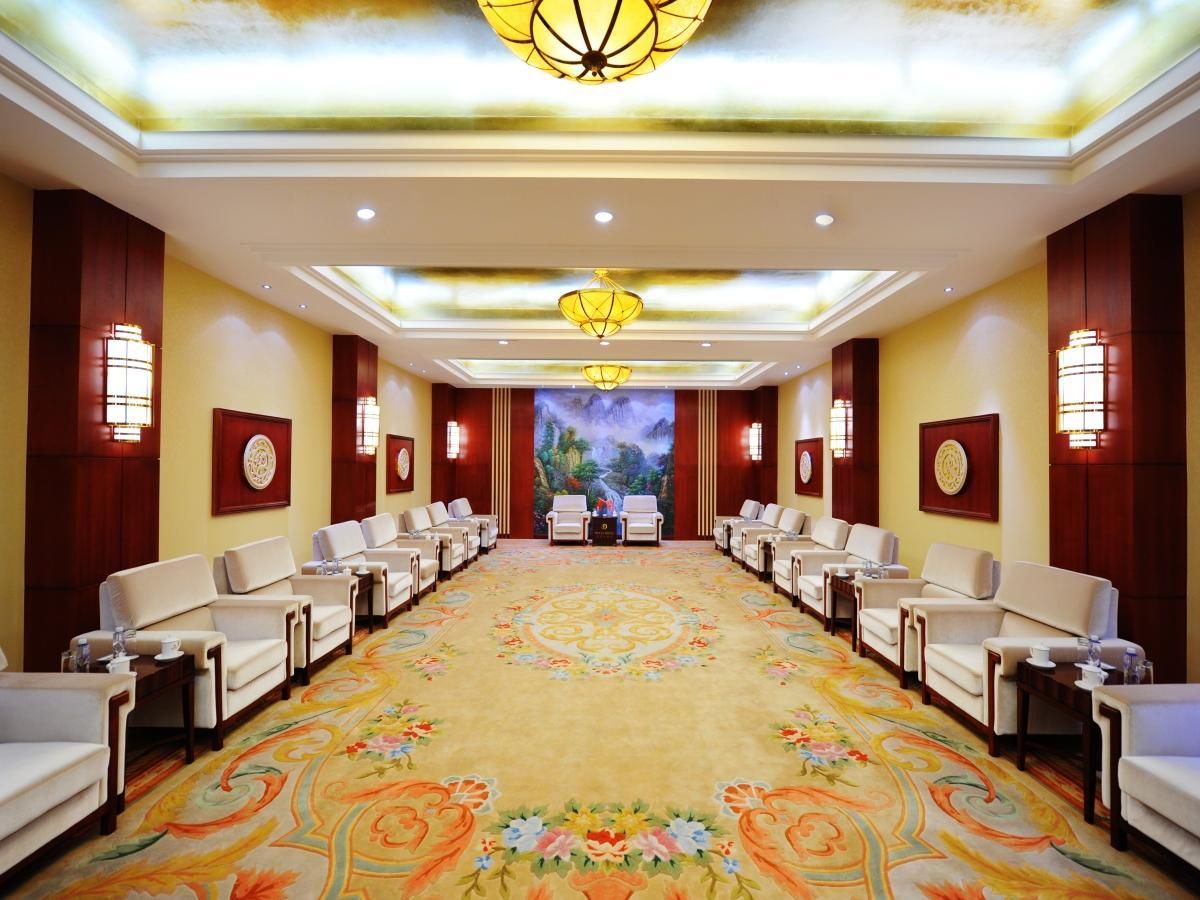A conference room with a long table, chairs, and a carpeted floor.