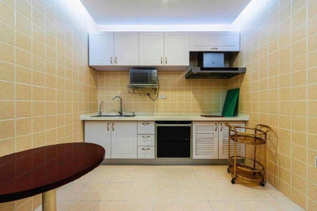 Une cuisine compacte avec des meubles blancs, un four à micro-ondes, un lave-vaisselle et une petite table à manger.