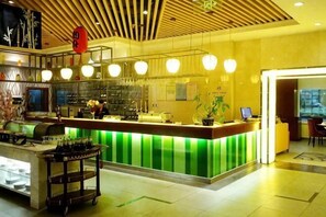 A hotel lobby with a reception desk, a bar area, and a seating area.