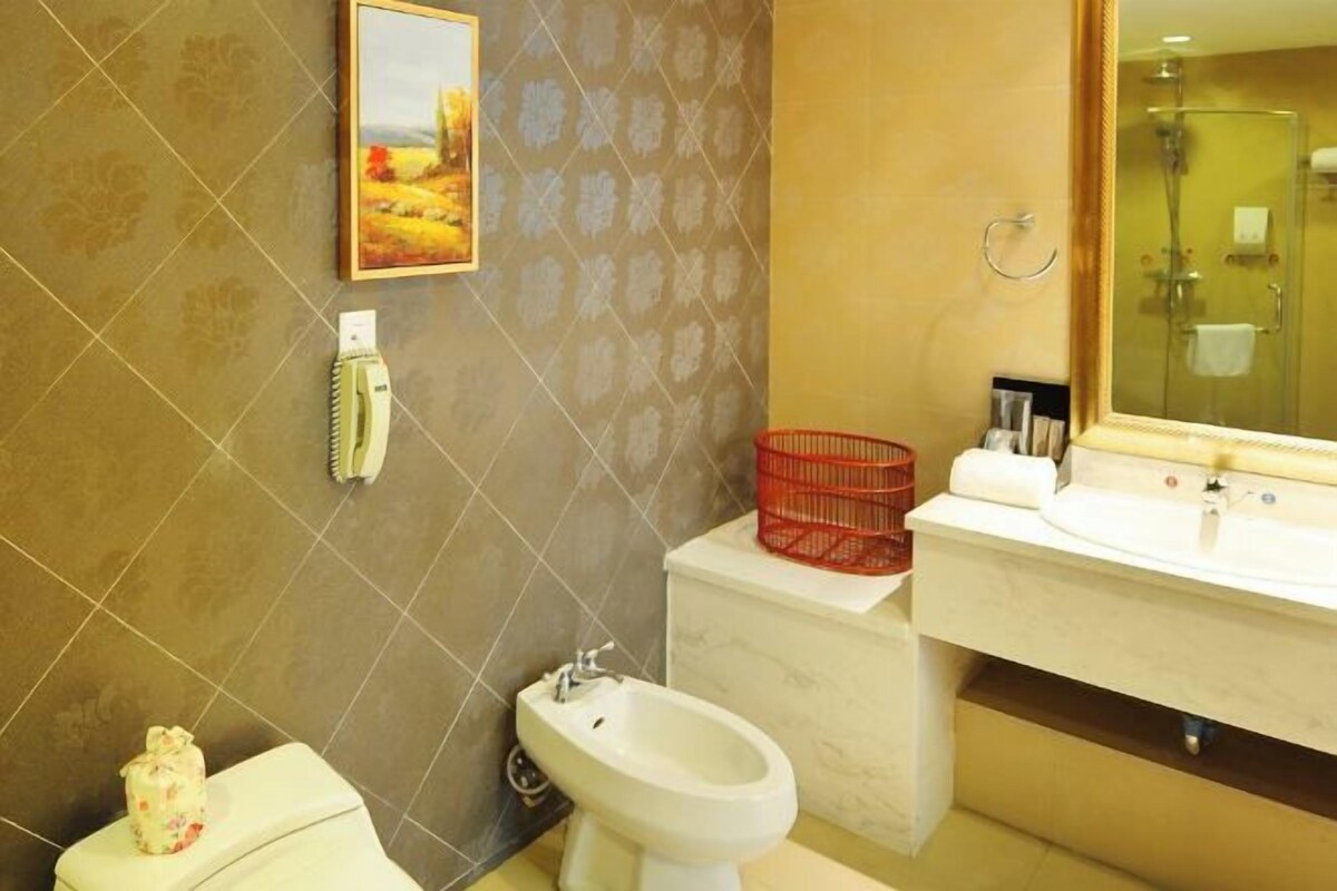 A bathroom with a toilet, bidet, sink, and a glass shower enclosure.