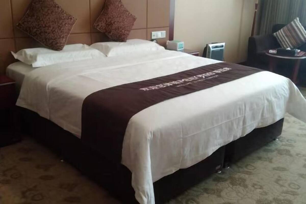 A hotel room with a large bed, a nightstand, a lamp, and a chair.