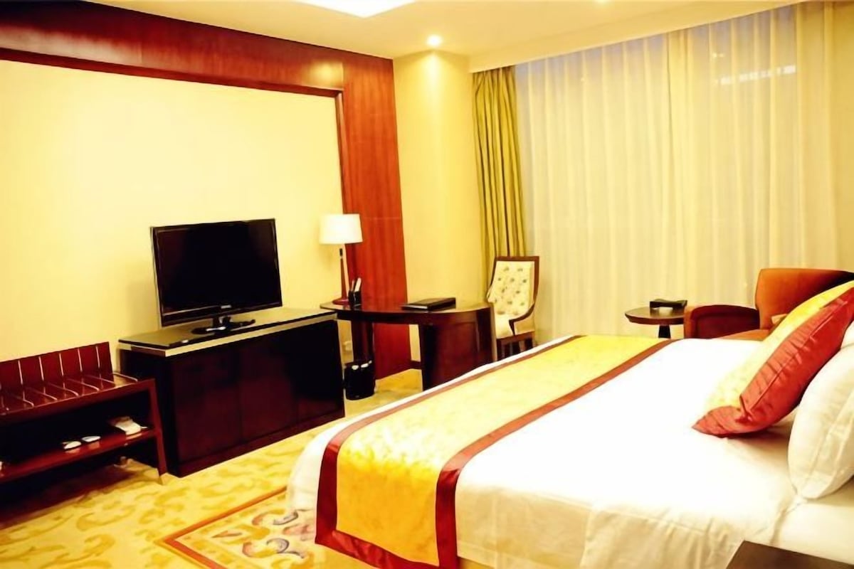 Une chambre d’hôtel avec un lit, une télévision, un bureau et une chaise.