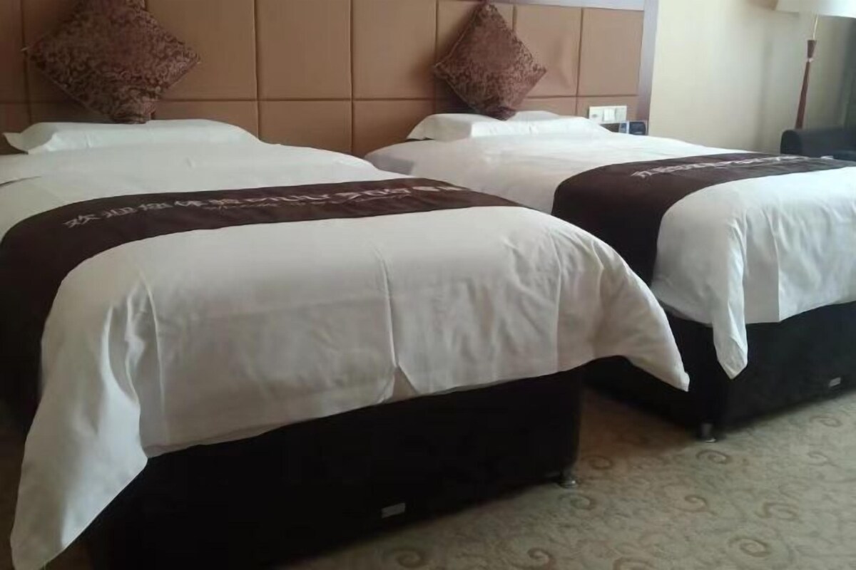 A hotel room with two beds, a headboard, and a carpeted floor.
