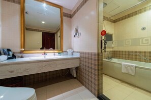 Une salle de bain avec un grand miroir, un lavabo, des toilettes et un espace douche.