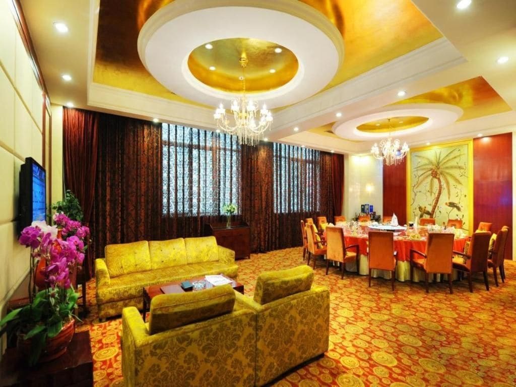 Habitación de hotel con sofá amarillo, zona de comedor con mesa dispuesta para cuatro personas y una araña.