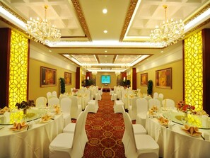 A banquet hall with round tables, white chairs, chandeliers, and a carpeted floor. - Chengyang Detai Hotel (Qingdao)