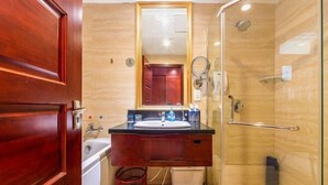 A bathroom with a wooden vanity, a mirror, a sink, and a glass shower enclosure. - Chengyang Detai Hotel (Qingdao)