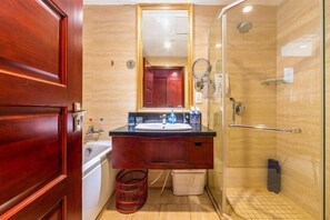 Une salle de bain avec un meuble-lavabo en bois, un miroir, un évier et une cabine de douche en verre.