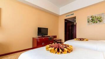 Habitación de hotel con dos camas, televisión, mueble de madera y un cuadro en la pared.