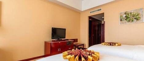 Quarto de hotel com duas camas, uma televisão, um armário de madeira e um quadro na parede.