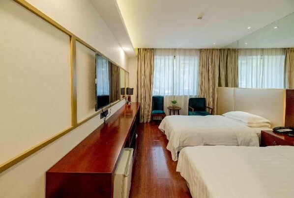 Habitación de hotel con cama, mesita de noche, lámpara, silla y un espejo grande.