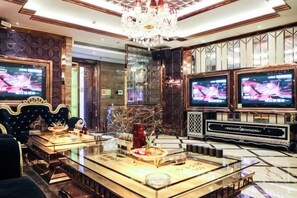 A luxurious lobby with a bar area, multiple screens, and a chandelier.