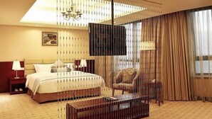 A hotel room with a large bed, a TV, a chair, and a wooden coffee table. - Chengdu Sovereign Hotel (Chengdu)
