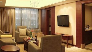 A modern living room with a sofa, armchairs, a coffee table, and a television mounted on the wall. - Chengdu Sovereign Hotel (Chengdu)