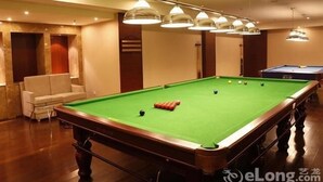 A pool table with balls, a sofa, and a billiard table in a room with wooden floors and ceiling lights. - Chengdu Sovereign Hotel (Chengdu)