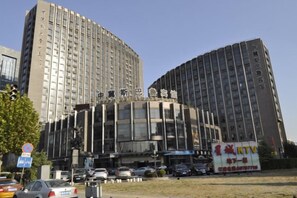 A multi-story building with a modern architectural design, featuring a prominent entrance with glass doors and a large sign above. - Zhong Ji Subaru Hotel (BEIJING)