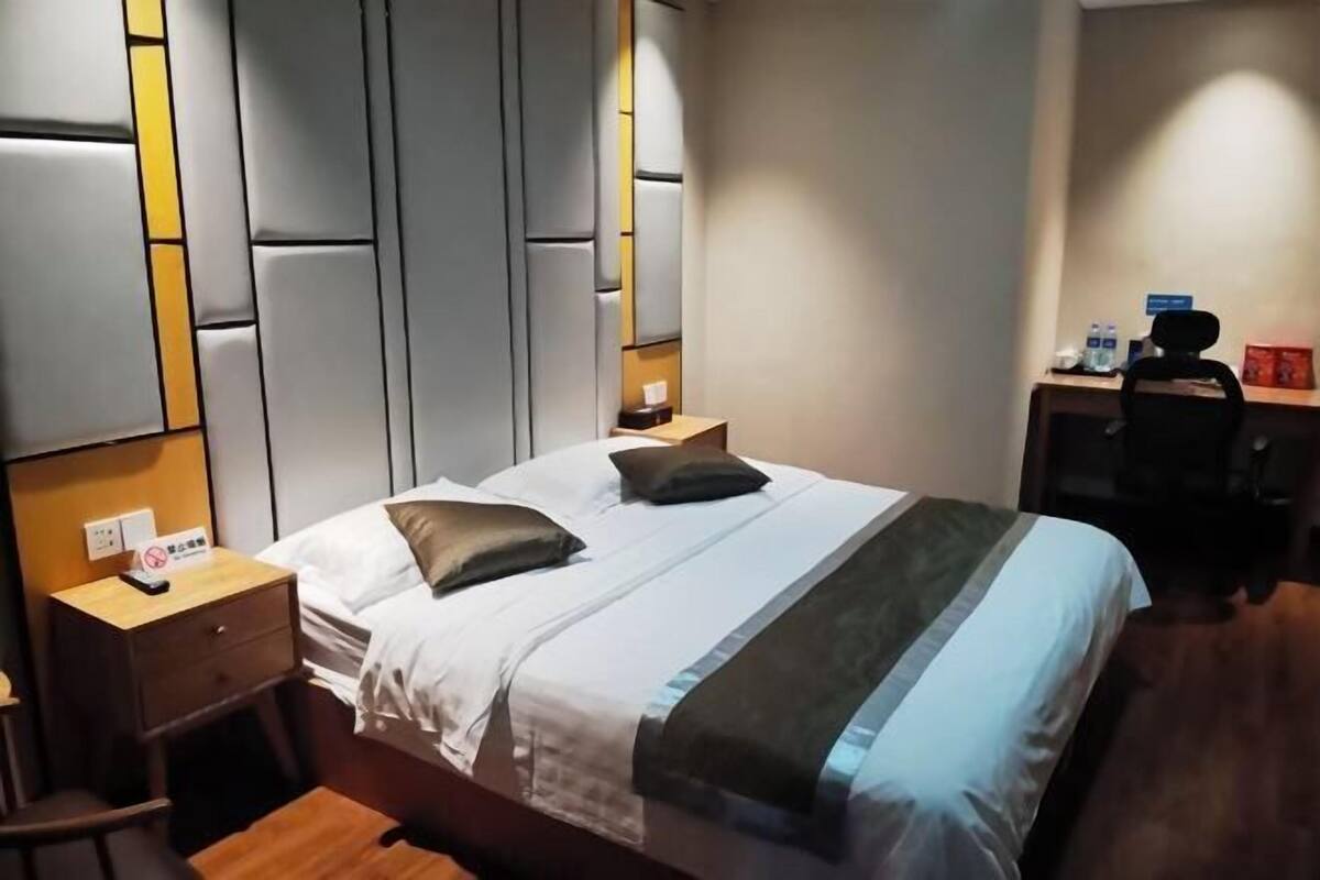 Una habitación de hotel con una cama, una mesita de noche, un escritorio y una silla.