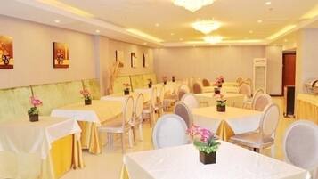 A banquet hall with round tables, white tablecloths, and chairs.