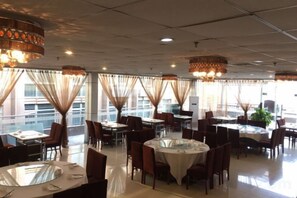 Ein Restaurant mit runden Tischen, Stühlen und hängenden Kronleuchtern.