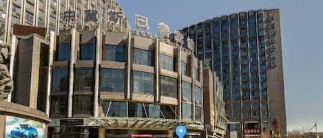 A modern hotel with a prominent entrance, multiple floors, and a parking area with cones.