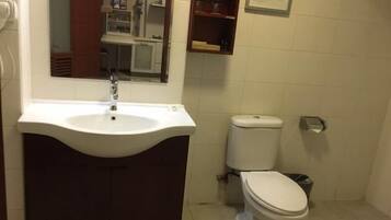 Een badkamer met een wit wastafel, een toilet en een spiegel boven het wastafel.