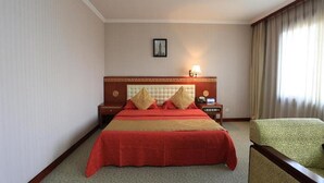 Une chambre d’hôtel avec un grand lit, une table de chevet, une lampe et une chaise.