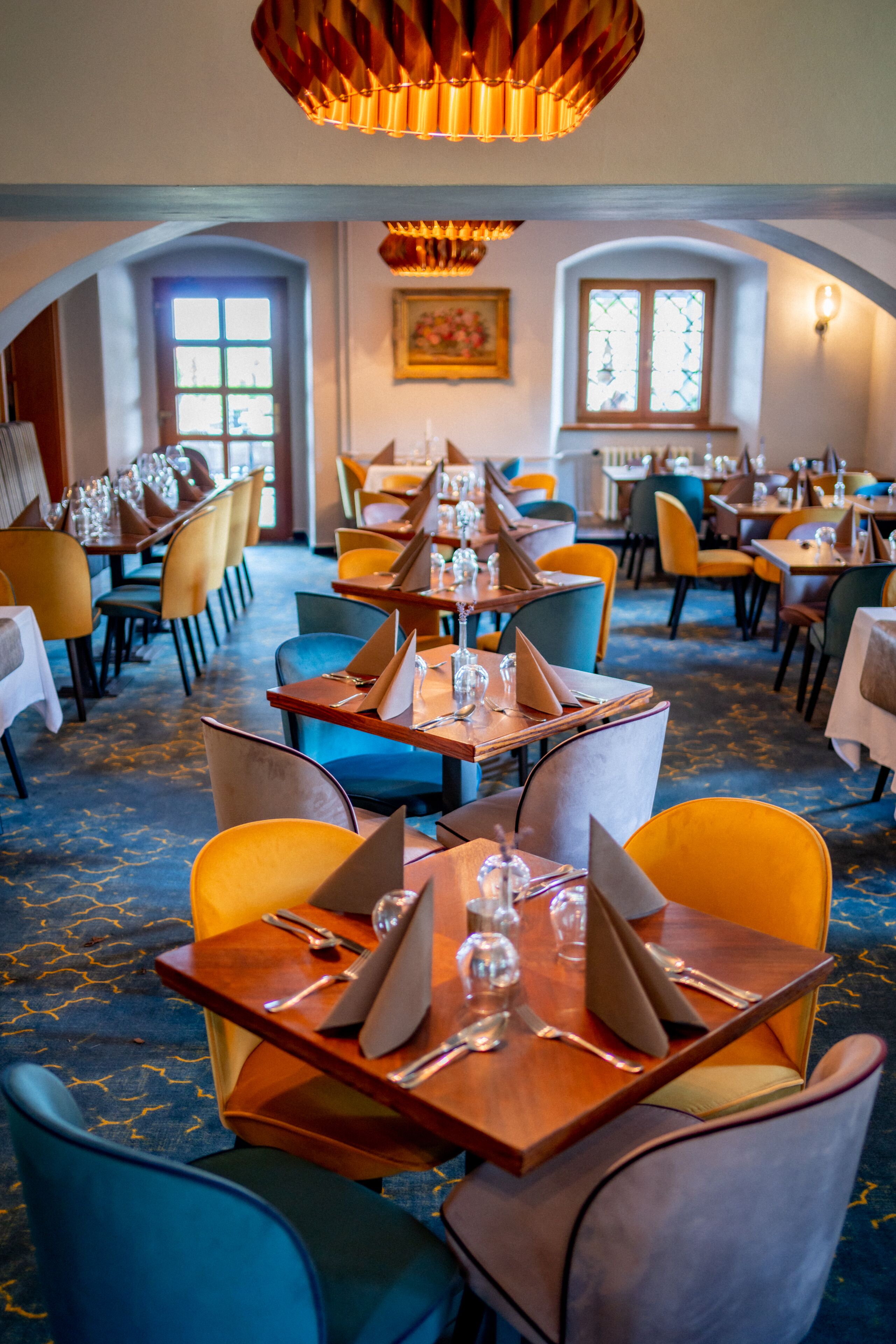 En restaurang med många bord och stolar, placerade i en rymlig och välplanerad lokal med en stor kristallkrona i taket.