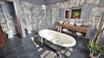 Un baño moderno con una bañera independiente, un tocador de madera, un espejo grande y una pared con estampado de mármol.