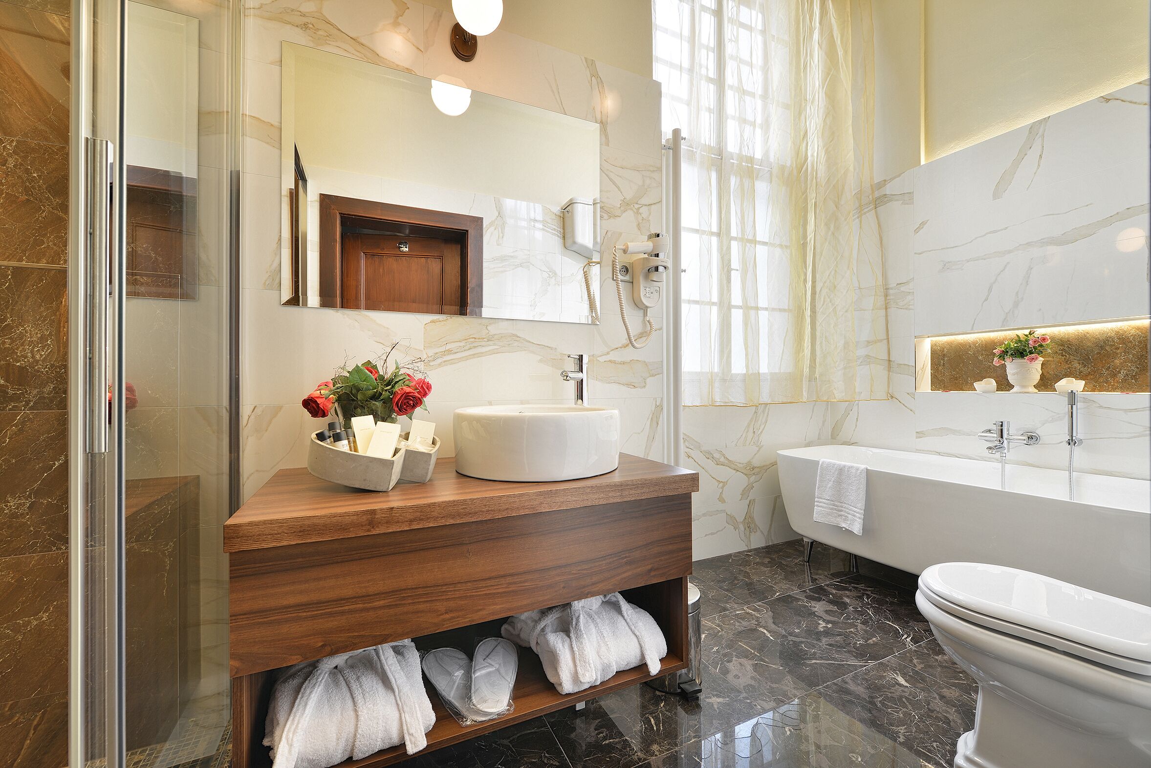 A modern bathroom with a marble vanity, a bathtub, and a toilet.