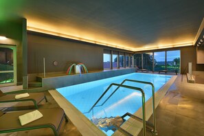 Een binnenzwembad, ligstoelen bij het zwembad
