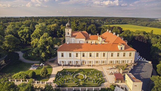 Un grand bâtiment historique à la façade symétrique, doté d’une cour intérieure avec une fontaine et d’une tour surmontée d’un dôme.