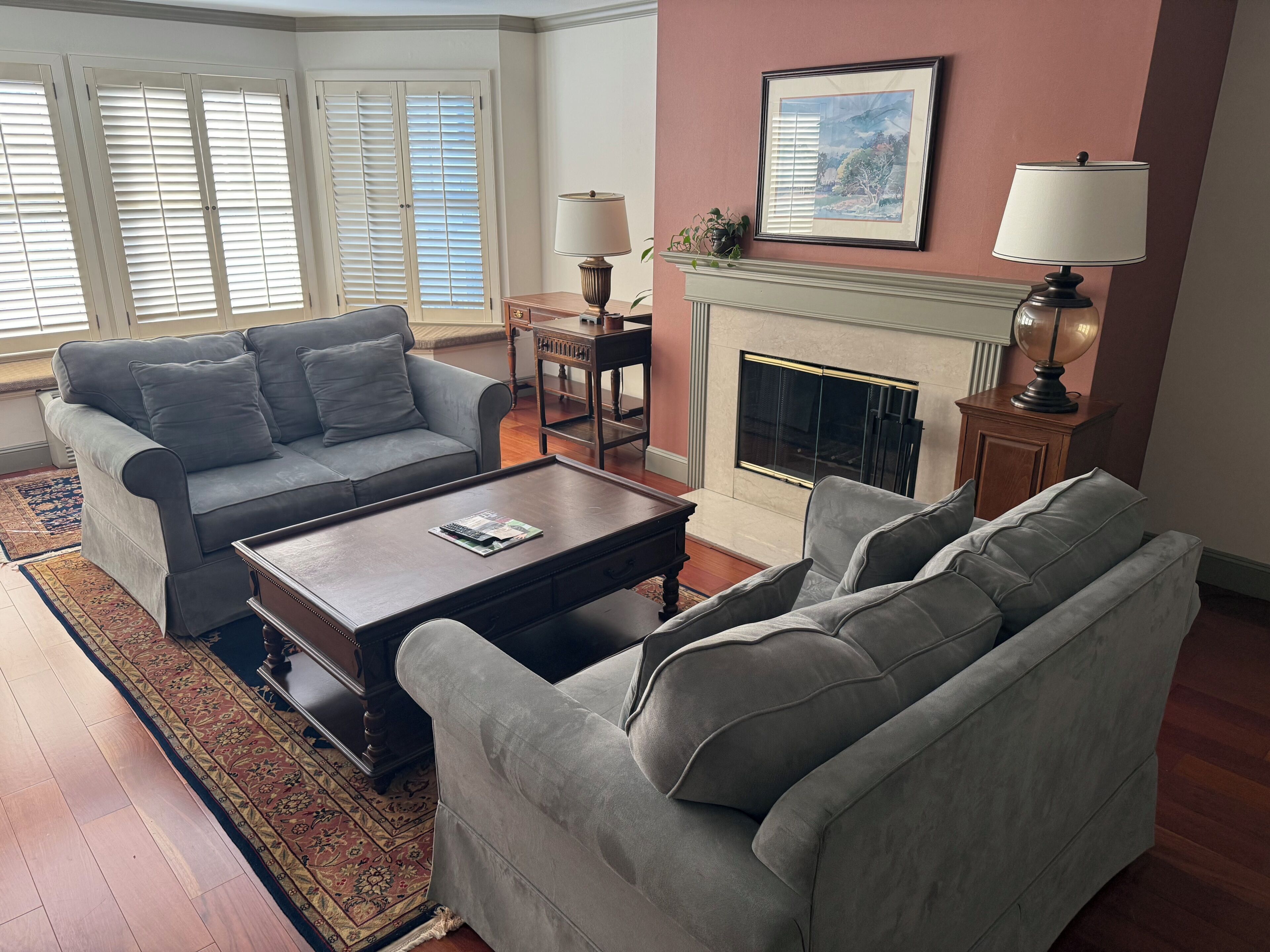 A living room with a grey sofa, a coffee table, a fireplace, and a framed picture on the wall.