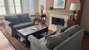 A living room with a grey sofa, a coffee table, a fireplace, and a framed picture on the wall.