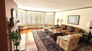 A living room with a sofa, armchair, coffee table, and a patterned rug.