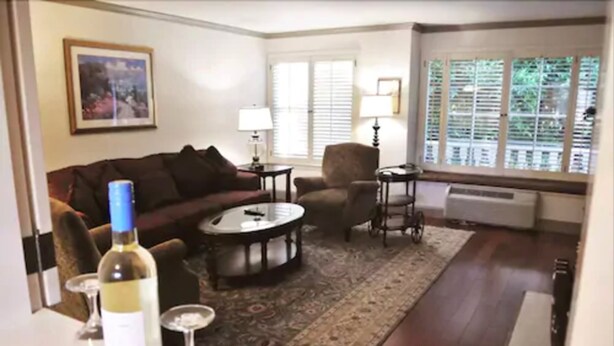 A living room with a sofa, armchair, coffee table, and a wine bottle.