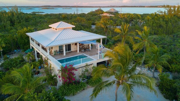 A two-story house with a pool, surrounded by tropical vegetation and overlooking a body of water. - Casa de Isle (Providenciales)
