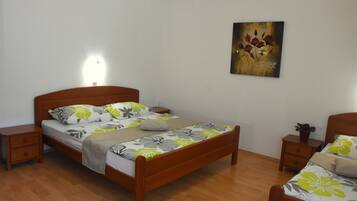 A bedroom with a wooden bed, a nightstand, a bedside table, and a wall-mounted painting.