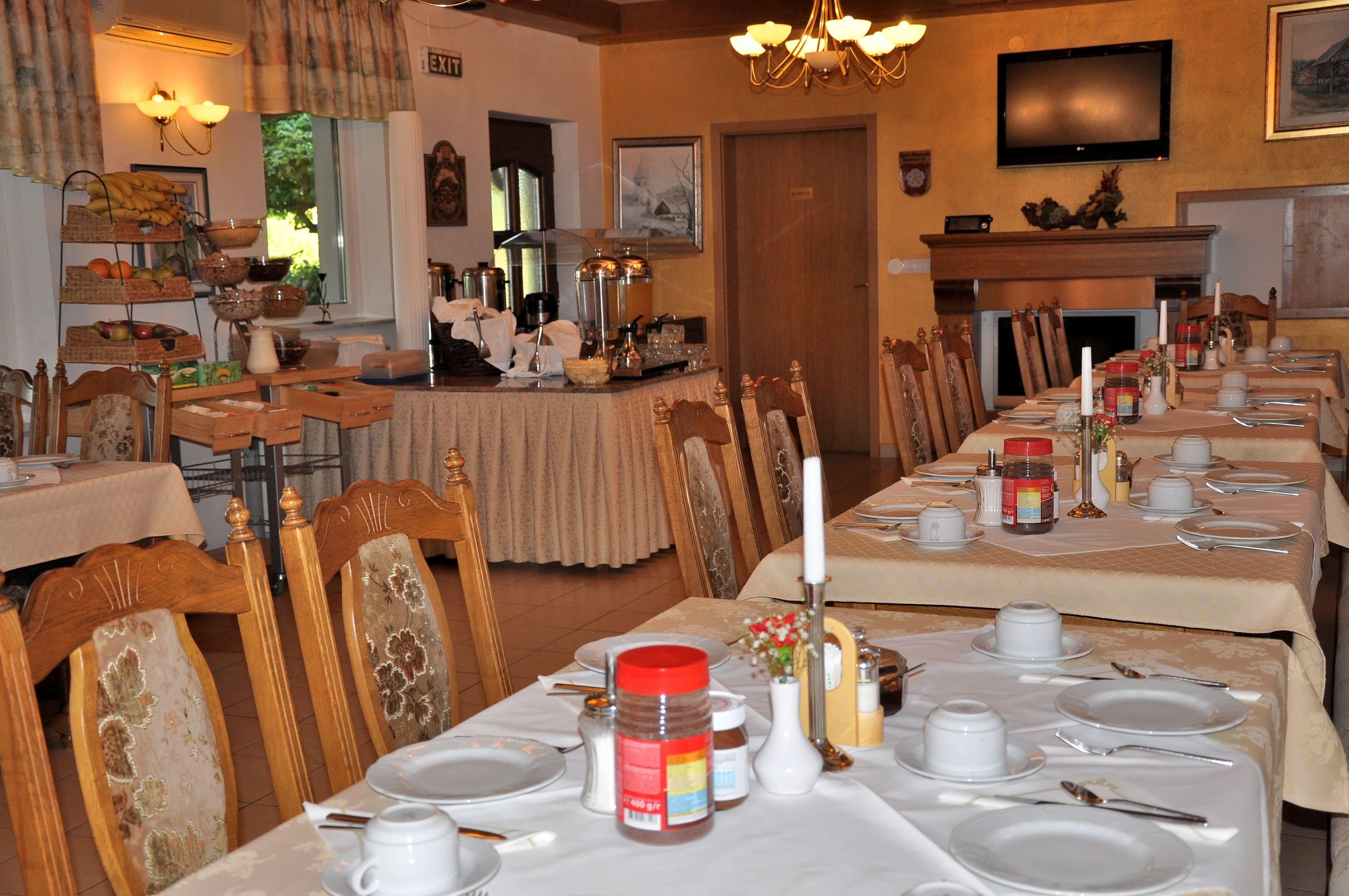 A dining area with multiple tables set for service, chairs, and a buffet with various food items.