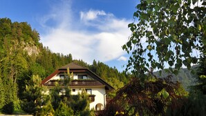 A two-story house with a balcony, surrounded by lush greenery and a mountainous backdrop. - Nature Hotel Lukanc Bled (Bled)