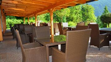 Un patio al aire libre con mobiliario de mimbre y una pérgola de madera.