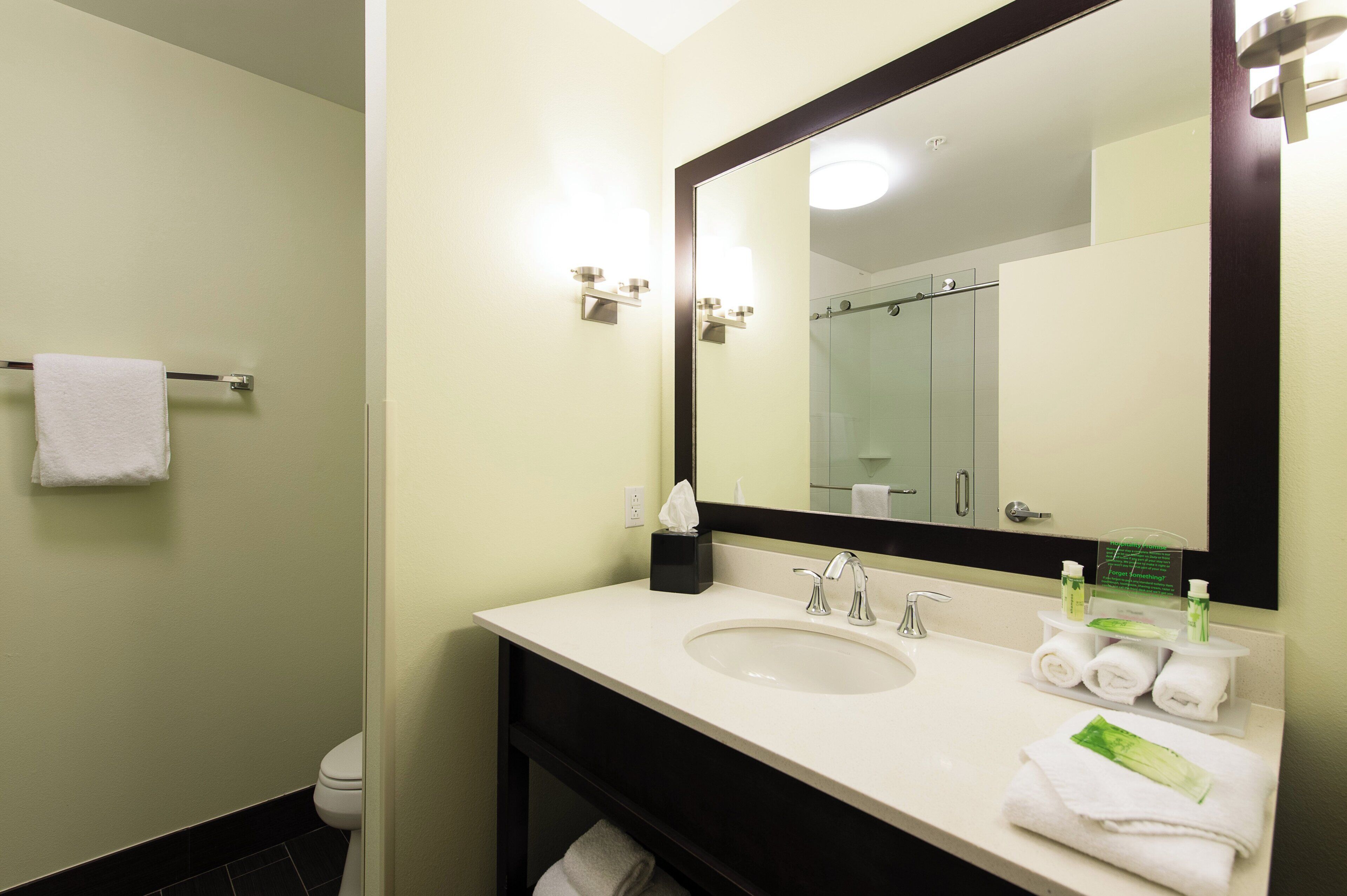 Une salle de bain avec un lavabo blanc, un miroir, un porte-serviettes et une cabine de douche en verre.