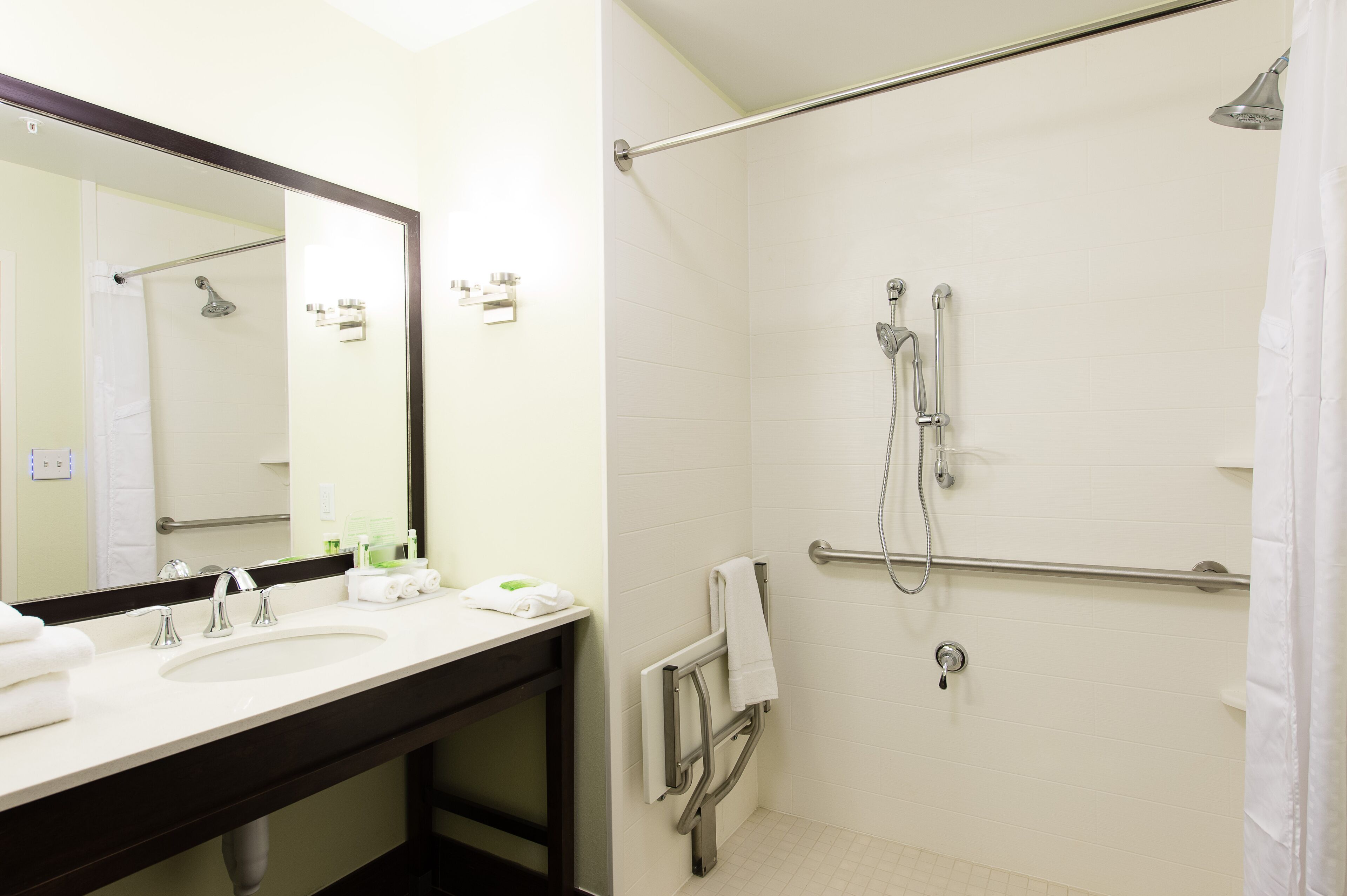 A bathroom with a sink, mirror, and shower.
