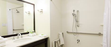 A bathroom with a sink, mirror, and shower.