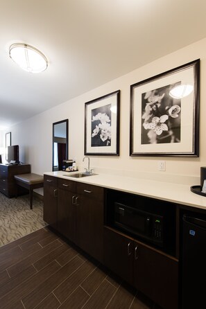 A modern bathroom with a dark wood vanity, a sink, and a mirror. There are framed black and white floral photographs on the wall. - Holiday Inn Express & Suites Aiken by IHG (Aiken)