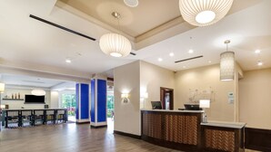 A spacious lobby with a reception desk, modern lighting fixtures, and a view into the dining area. - Holiday Inn Express & Suites Aiken by IHG (Aiken)