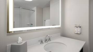 A modern bathroom with a large mirror, a white sink, and two Dove hand soap dispensers on the wall.