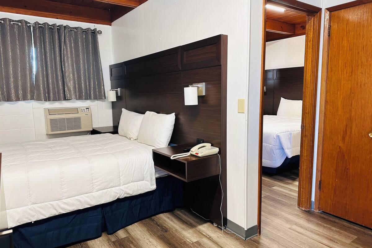 Camera d'albergo con un letto grande, un comodino e una testiera in legno.