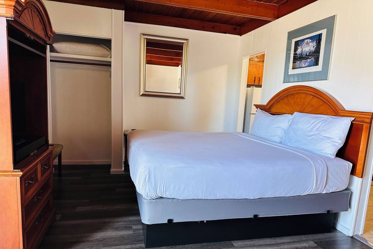 Una camera da letto con un letto, un armadio in legno e un quadro appeso al muro.