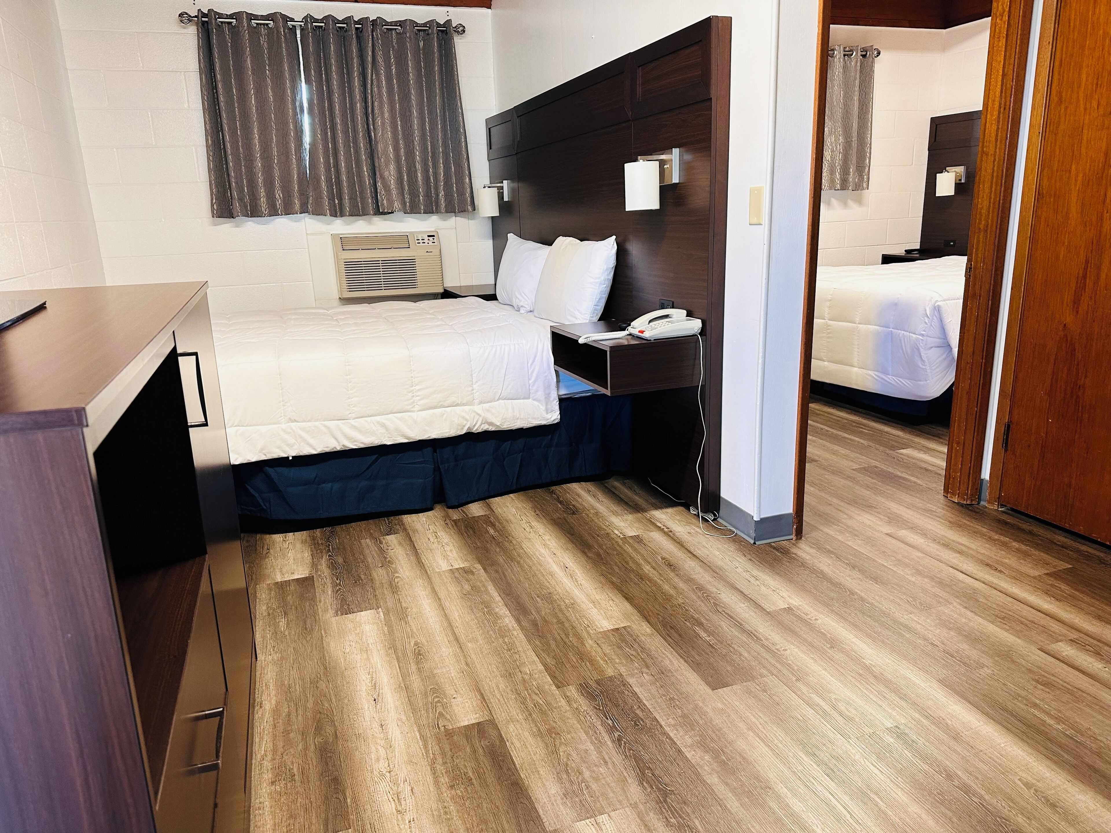 A hotel room with a bed, bedside table, lamp, and a telephone.